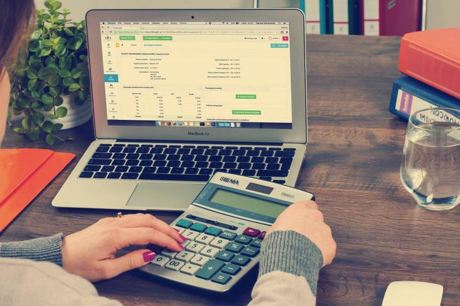 A desk with a laptop, a calculator and invoices