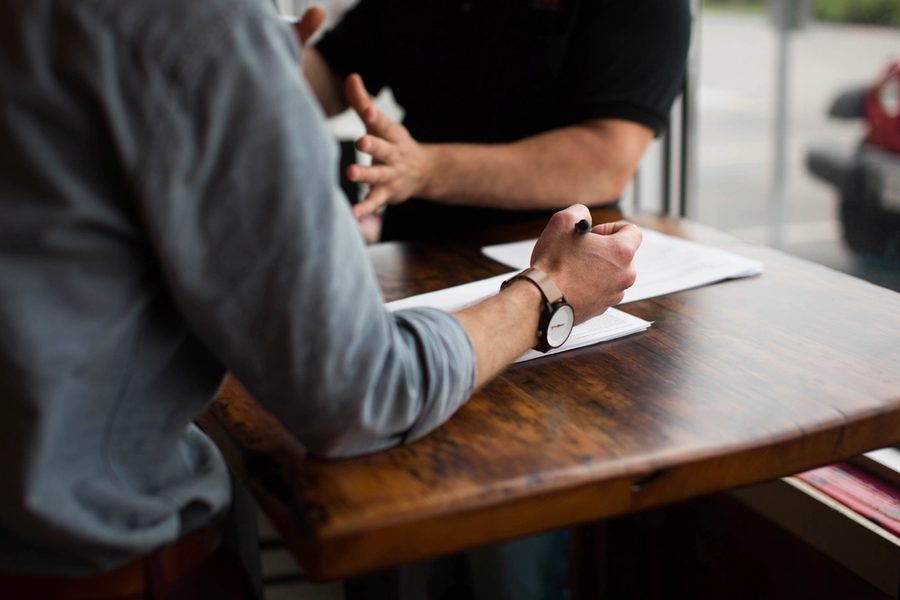 Two people talking at a meeting table with documents
