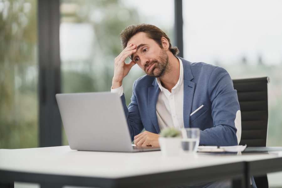 A worried person at a laptop in an office